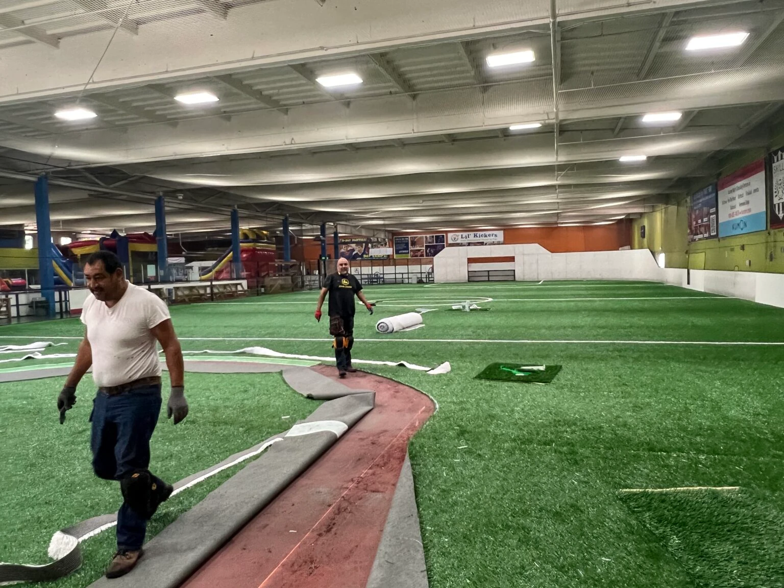 TSS installation crew rolling out an indoor turf field